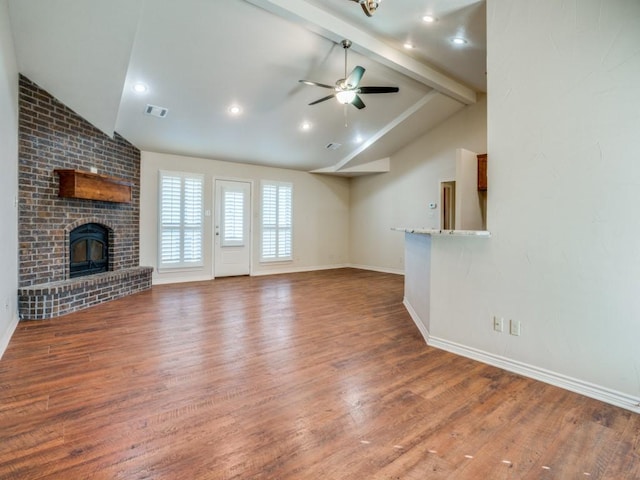 unfurnished living room with hardwood / wood-style flooring, a fireplace, lofted ceiling with beams, and ceiling fan