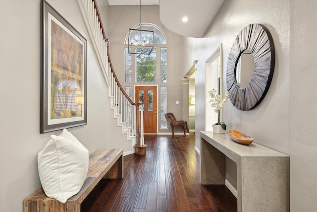 foyer entrance with a towering ceiling, dark hardwood / wood-style floors, and a chandelier