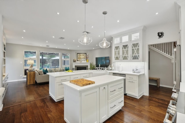 kitchen featuring a kitchen island, white cabinetry, dark hardwood / wood-style flooring, pendant lighting, and kitchen peninsula