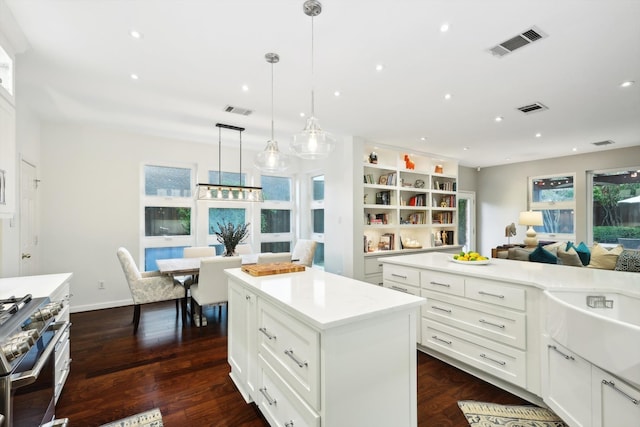 kitchen with high end stove, white cabinetry, dark hardwood / wood-style floors, pendant lighting, and a center island