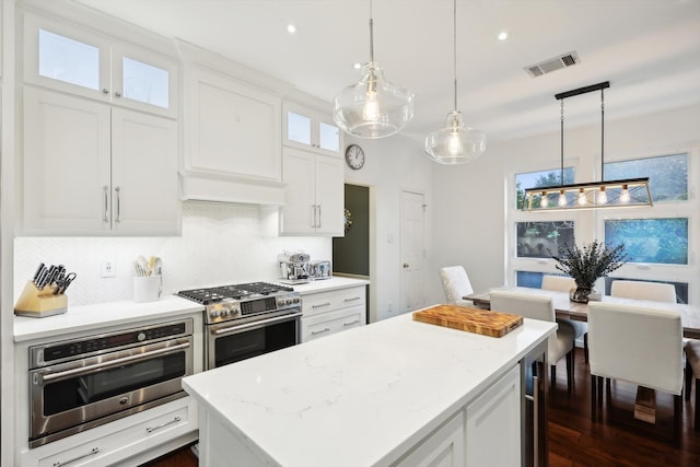 kitchen with dark hardwood / wood-style flooring, a center island, hanging light fixtures, white cabinetry, and appliances with stainless steel finishes