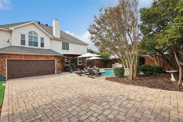 rear view of house featuring a garage and a fenced in pool