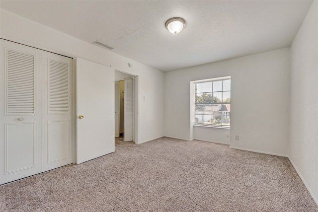 unfurnished bedroom featuring light carpet and a closet