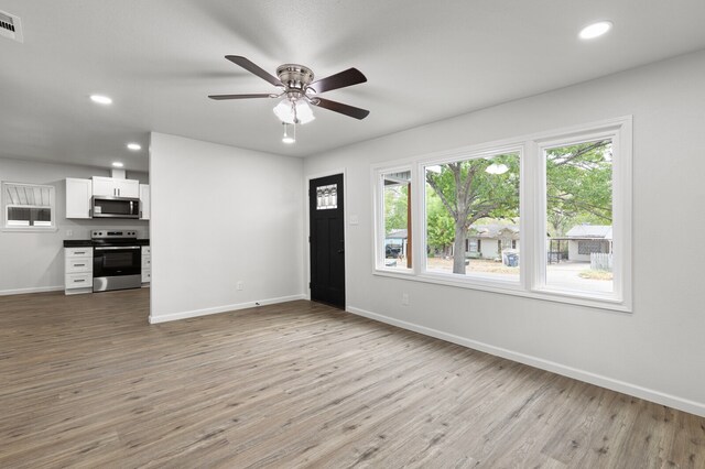 unfurnished living room with ceiling fan and light hardwood / wood-style flooring