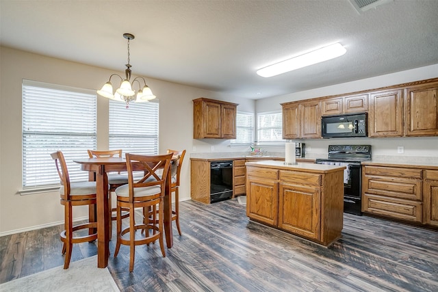 kitchen with black appliances, a kitchen island, dark hardwood / wood-style flooring, hanging light fixtures, and an inviting chandelier