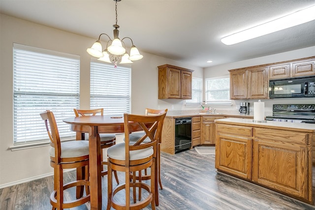 kitchen featuring black appliances, hanging light fixtures, sink, dark wood-type flooring, and a chandelier