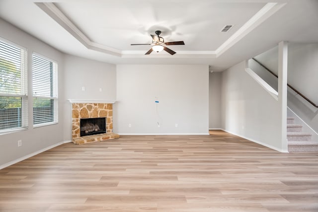 unfurnished living room featuring a fireplace, light hardwood / wood-style floors, and a raised ceiling