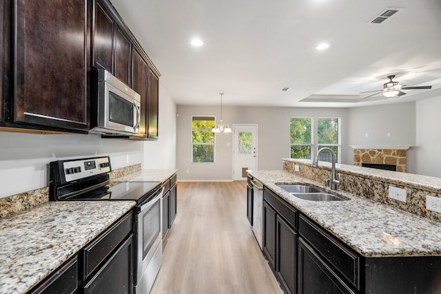 kitchen featuring light stone counters, sink, light wood-type flooring, and appliances with stainless steel finishes