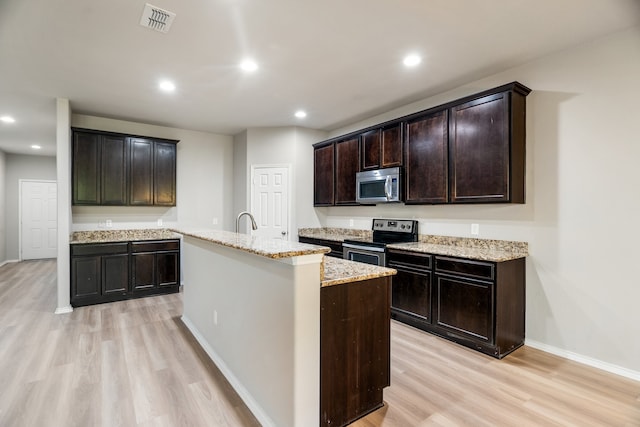 kitchen with dark brown cabinetry, light wood-type flooring, appliances with stainless steel finishes, and an island with sink