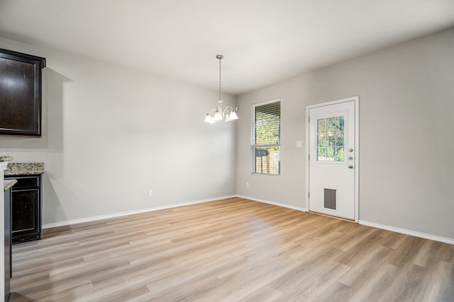 unfurnished dining area featuring light wood-type flooring and a notable chandelier