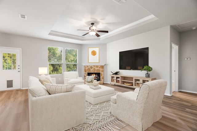 living room with hardwood / wood-style floors, ceiling fan, and a tray ceiling