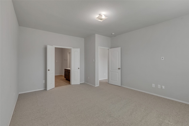 unfurnished bedroom with light colored carpet and ensuite bath