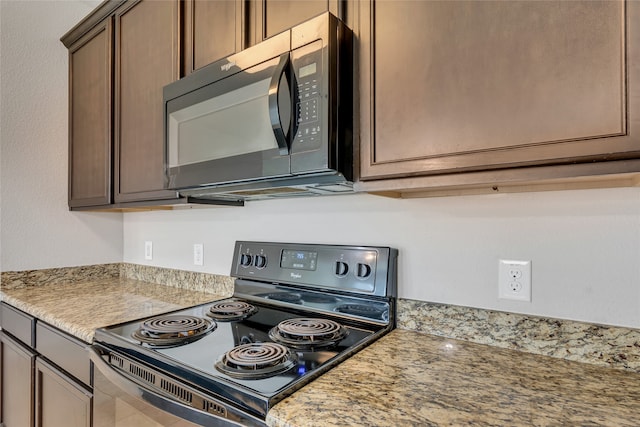 kitchen featuring light stone countertops, tile patterned floors, and black appliances