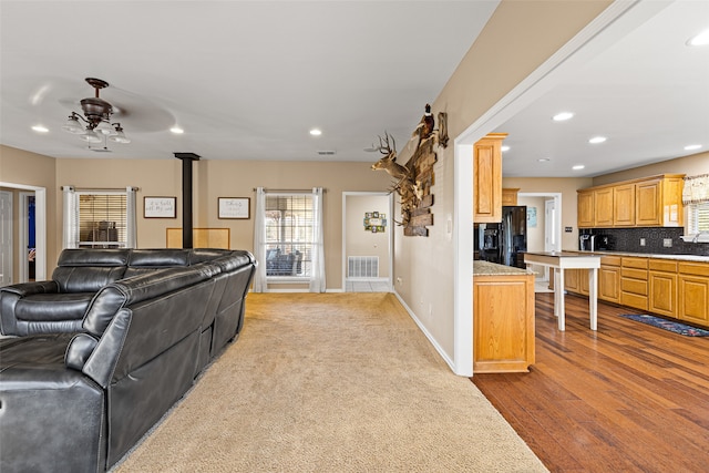 living room featuring a wood stove, light wood-type flooring, ceiling fan, and sink