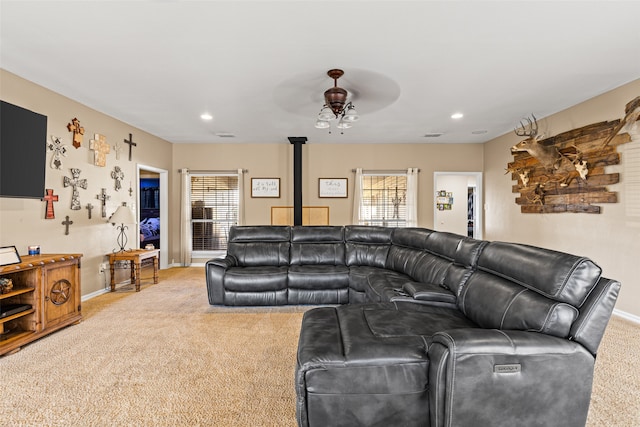 carpeted living room featuring a wood stove and ceiling fan