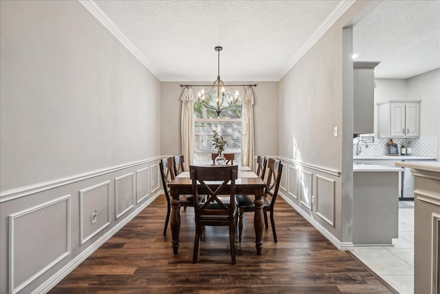 dining area featuring sink, dark hardwood / wood-style flooring, crown molding, a chandelier, and a textured ceiling