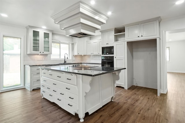 kitchen with white cabinetry, dark hardwood / wood-style flooring, black appliances, and a kitchen island