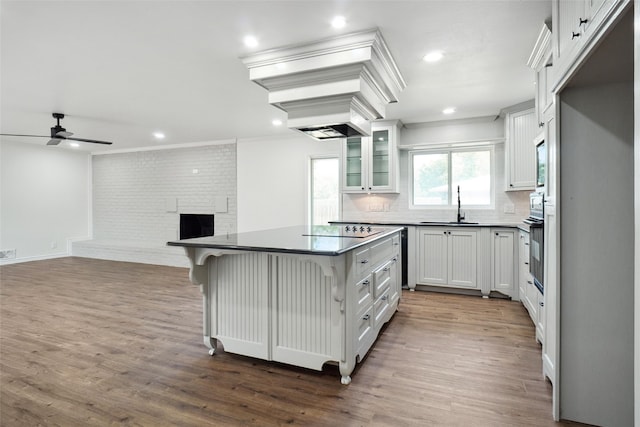 kitchen featuring crown molding, a kitchen island, dark hardwood / wood-style flooring, sink, and white cabinets