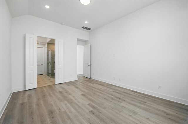 unfurnished bedroom featuring visible vents, baseboards, light wood finished floors, and vaulted ceiling