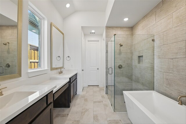 bathroom with a stall shower, a soaking tub, double vanity, and vaulted ceiling