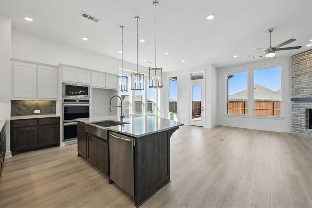 kitchen featuring open floor plan, a sink, light wood-style flooring, and stainless steel appliances