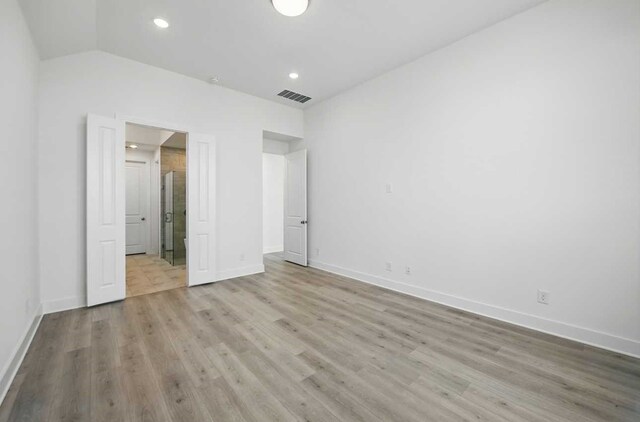 unfurnished bedroom with visible vents, baseboards, vaulted ceiling, and wood finished floors