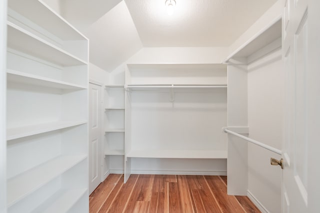 walk in closet featuring vaulted ceiling and light hardwood / wood-style floors