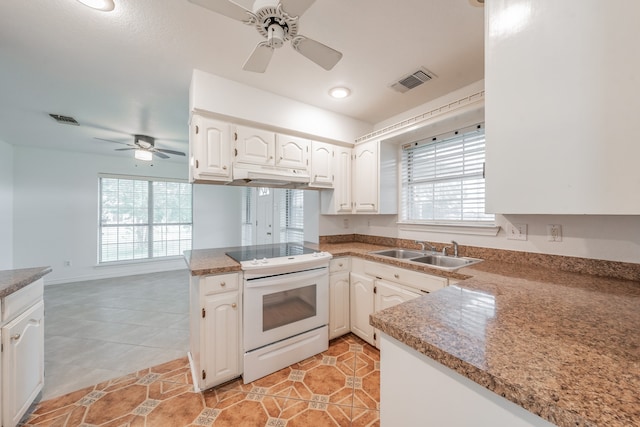 kitchen with a wealth of natural light, sink, white cabinets, kitchen peninsula, and electric range