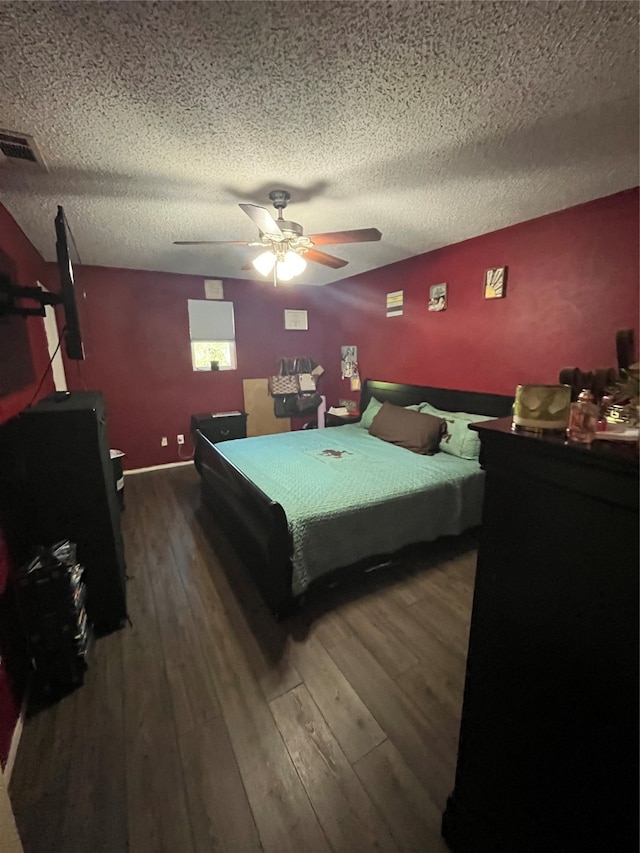 bedroom with ceiling fan, a textured ceiling, and dark hardwood / wood-style flooring