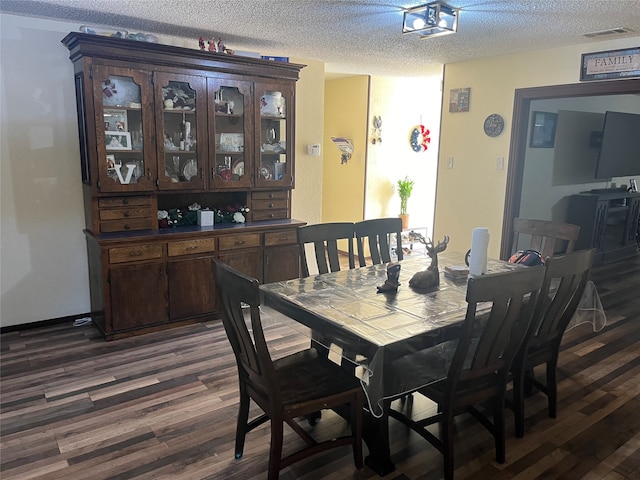 dining room featuring dark wood-type flooring and a textured ceiling