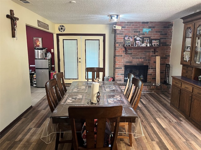 dining area with dark wood-type flooring, a textured ceiling, and a fireplace