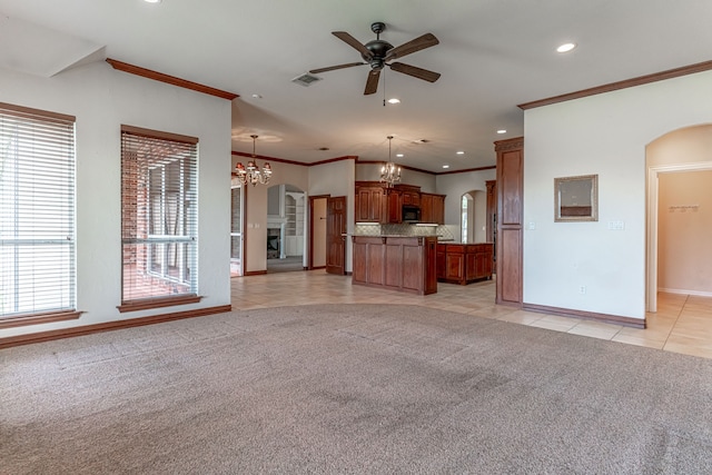 unfurnished living room with ornamental molding, ceiling fan with notable chandelier, and light colored carpet