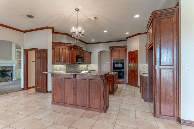 kitchen featuring black appliances, decorative light fixtures, light tile patterned floors, a notable chandelier, and light stone countertops