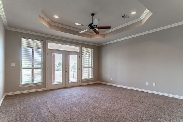 carpeted spare room with ceiling fan, a raised ceiling, french doors, and ornamental molding