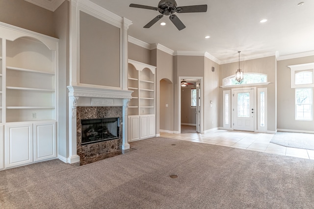 unfurnished living room featuring built in features, light tile patterned floors, a premium fireplace, and crown molding