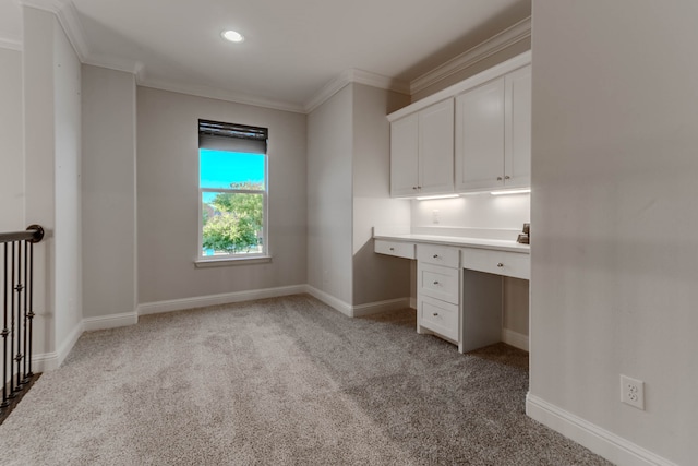 unfurnished office with light colored carpet, built in desk, and crown molding