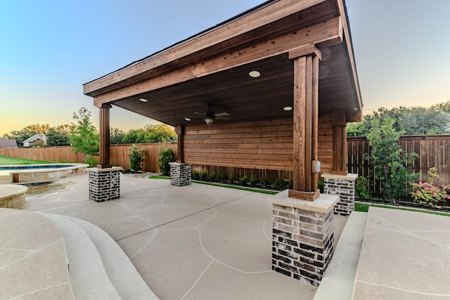 patio terrace at dusk featuring ceiling fan and a fenced in pool