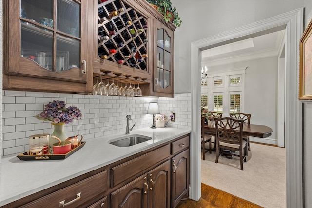 kitchen with ornamental molding, dark brown cabinetry, dark hardwood / wood-style floors, decorative backsplash, and sink