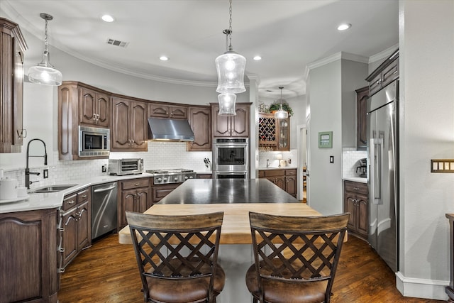 kitchen with built in appliances, sink, dark hardwood / wood-style floors, decorative light fixtures, and decorative backsplash