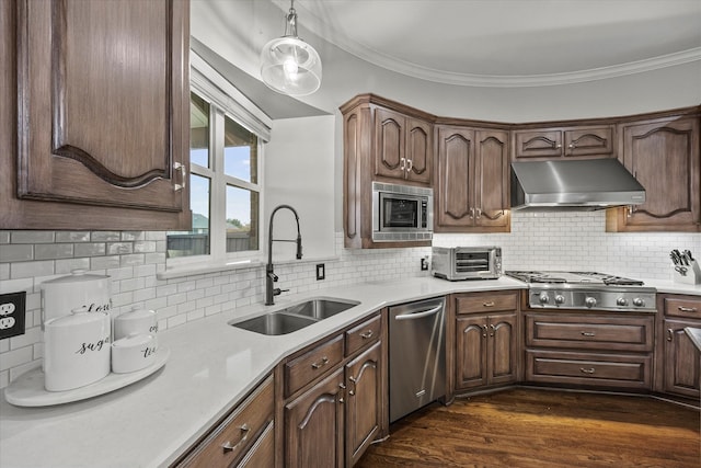 kitchen featuring appliances with stainless steel finishes, decorative backsplash, ornamental molding, and dark hardwood / wood-style floors