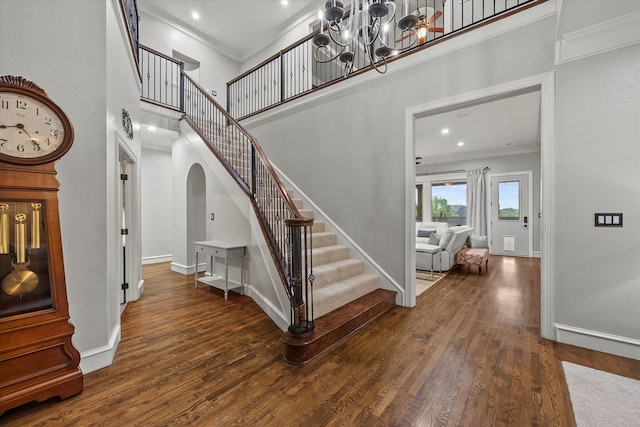 staircase with hardwood / wood-style flooring, ornamental molding, and a towering ceiling