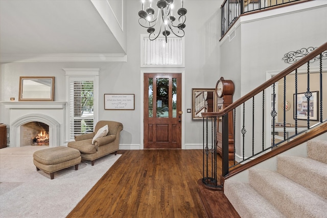 foyer with hardwood / wood-style flooring, a high ceiling, a chandelier, and ornamental molding