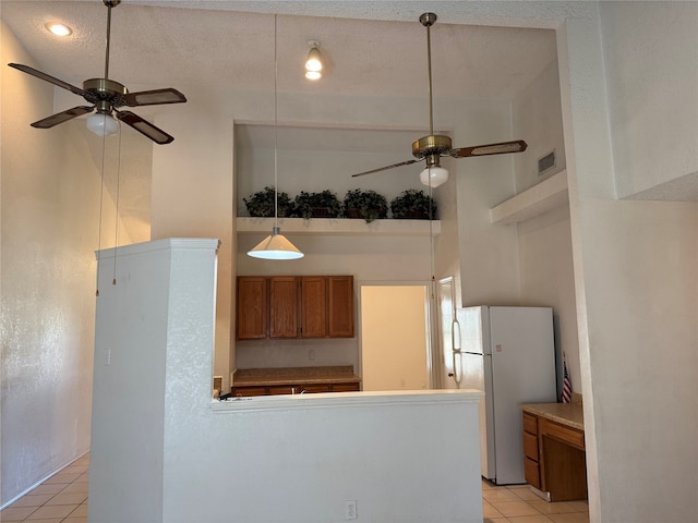 kitchen with a towering ceiling, a textured ceiling, light tile patterned floors, and white refrigerator