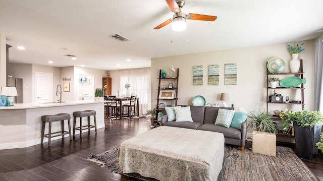 living room featuring dark hardwood / wood-style flooring, ceiling fan, and sink