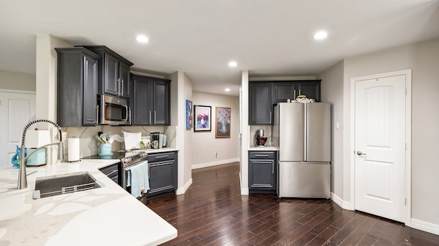 kitchen with stainless steel appliances, light stone countertops, sink, and dark hardwood / wood-style flooring