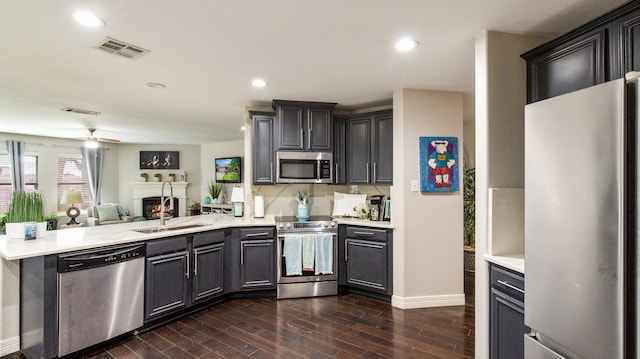 kitchen with stainless steel appliances, dark hardwood / wood-style flooring, sink, kitchen peninsula, and ceiling fan