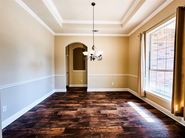 unfurnished dining area with dark wood-type flooring, a chandelier, a tray ceiling, and ornamental molding