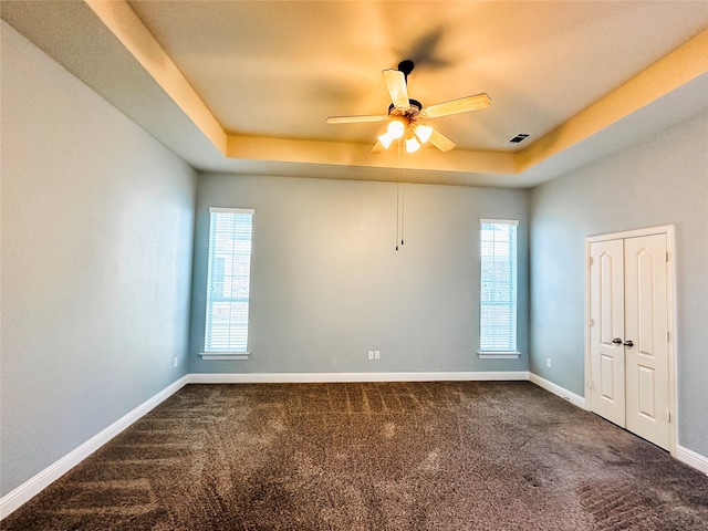 carpeted empty room featuring a tray ceiling, a wealth of natural light, and ceiling fan