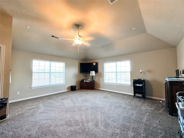 unfurnished living room with ceiling fan, dark carpet, and plenty of natural light