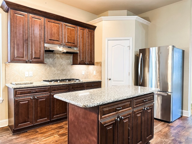 kitchen with light stone counters, dark hardwood / wood-style floors, a kitchen island, backsplash, and appliances with stainless steel finishes